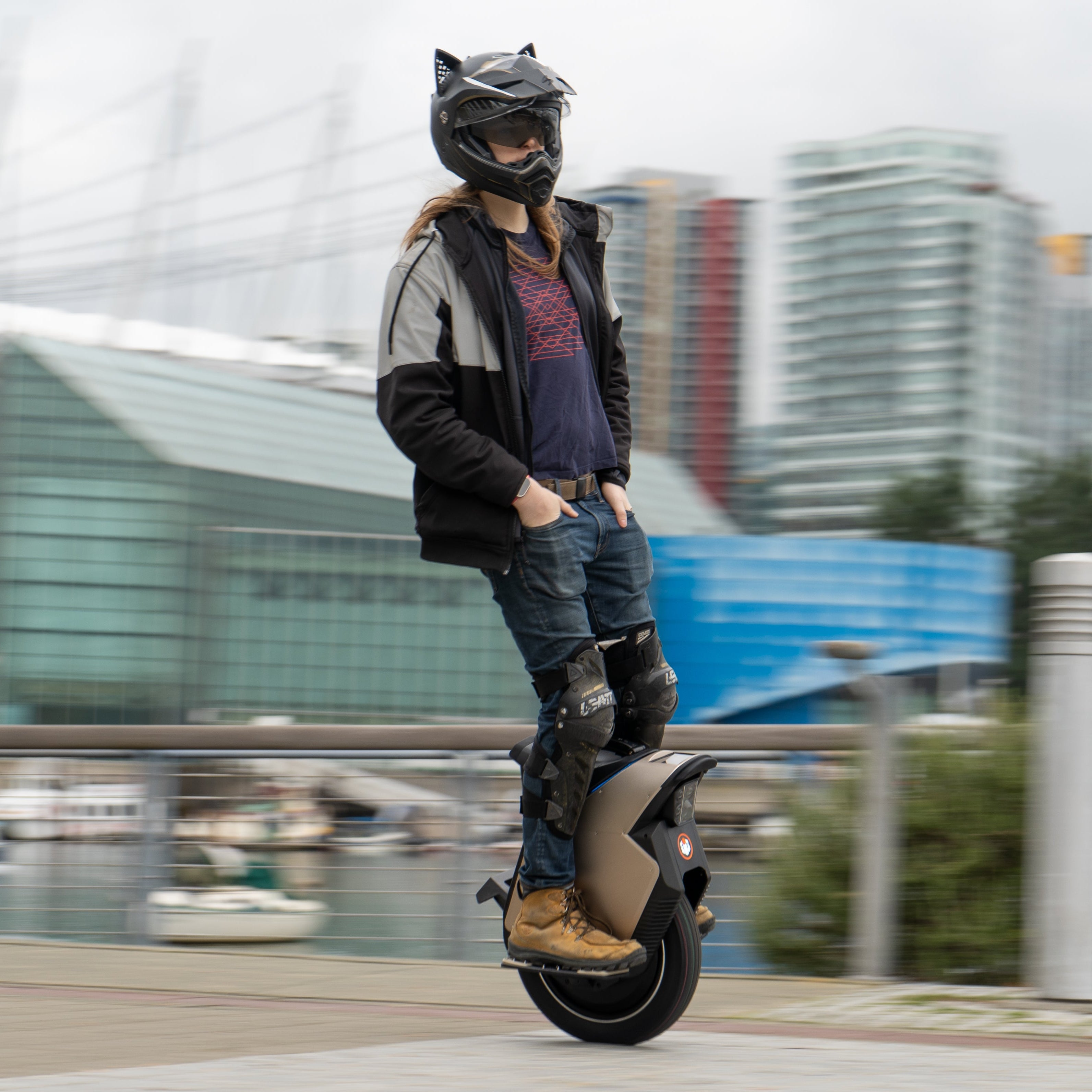 Person riding an electric unicycle on a city street with modern buildings in the background